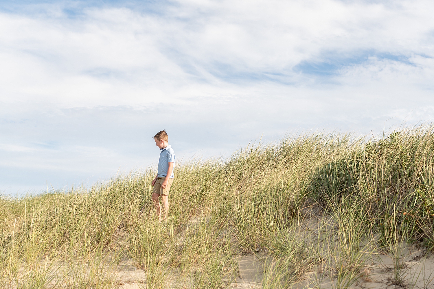 boy stands on dunes after learning top locations in Nantucket for your family photo session