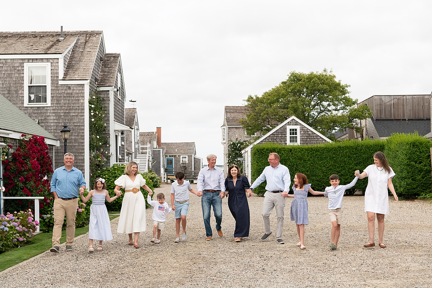 extended family walks down street together hand in hand by Massachusetts photographer