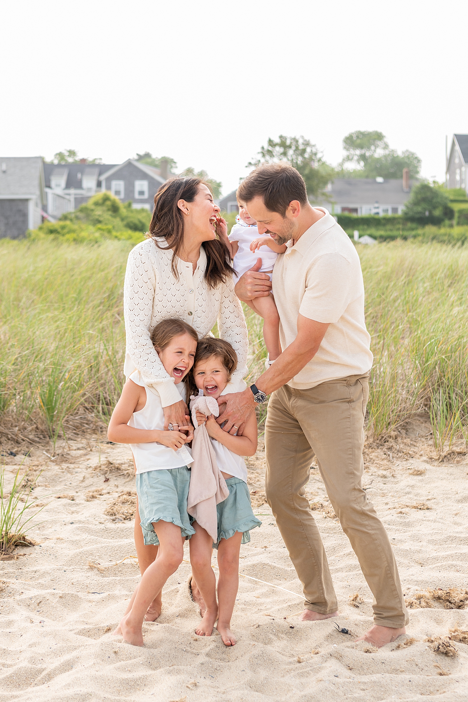 family of five laughs together near the sea grass by Rachel Elizabeth Co
