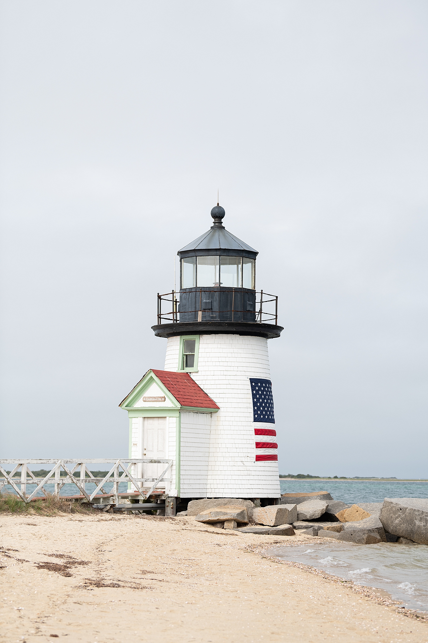 Patriotic lighthouse stands over the water by Rachel Elizabeth Photography