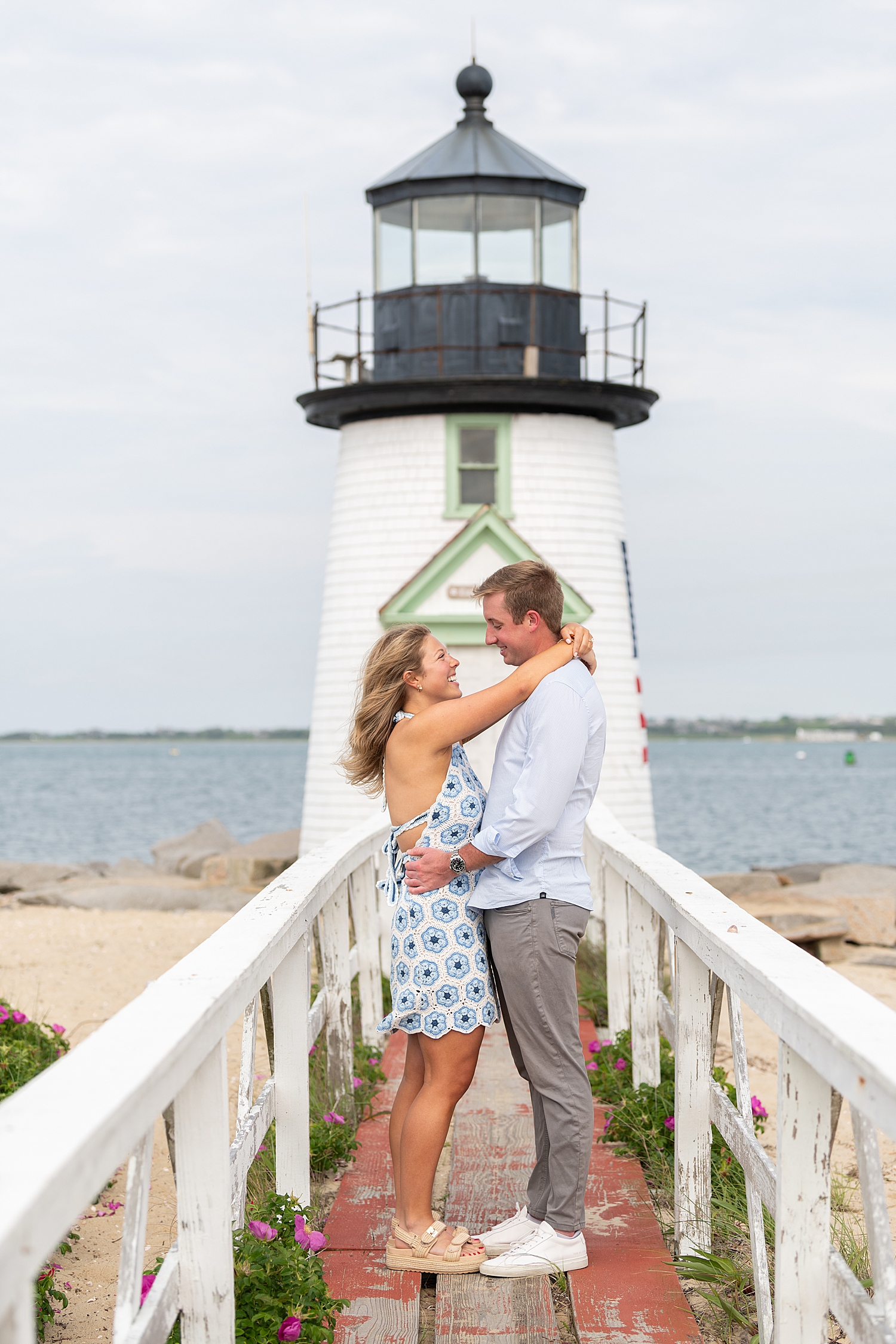 man and woman stand in front of ocean for proposal at Brant Point Lighthouse