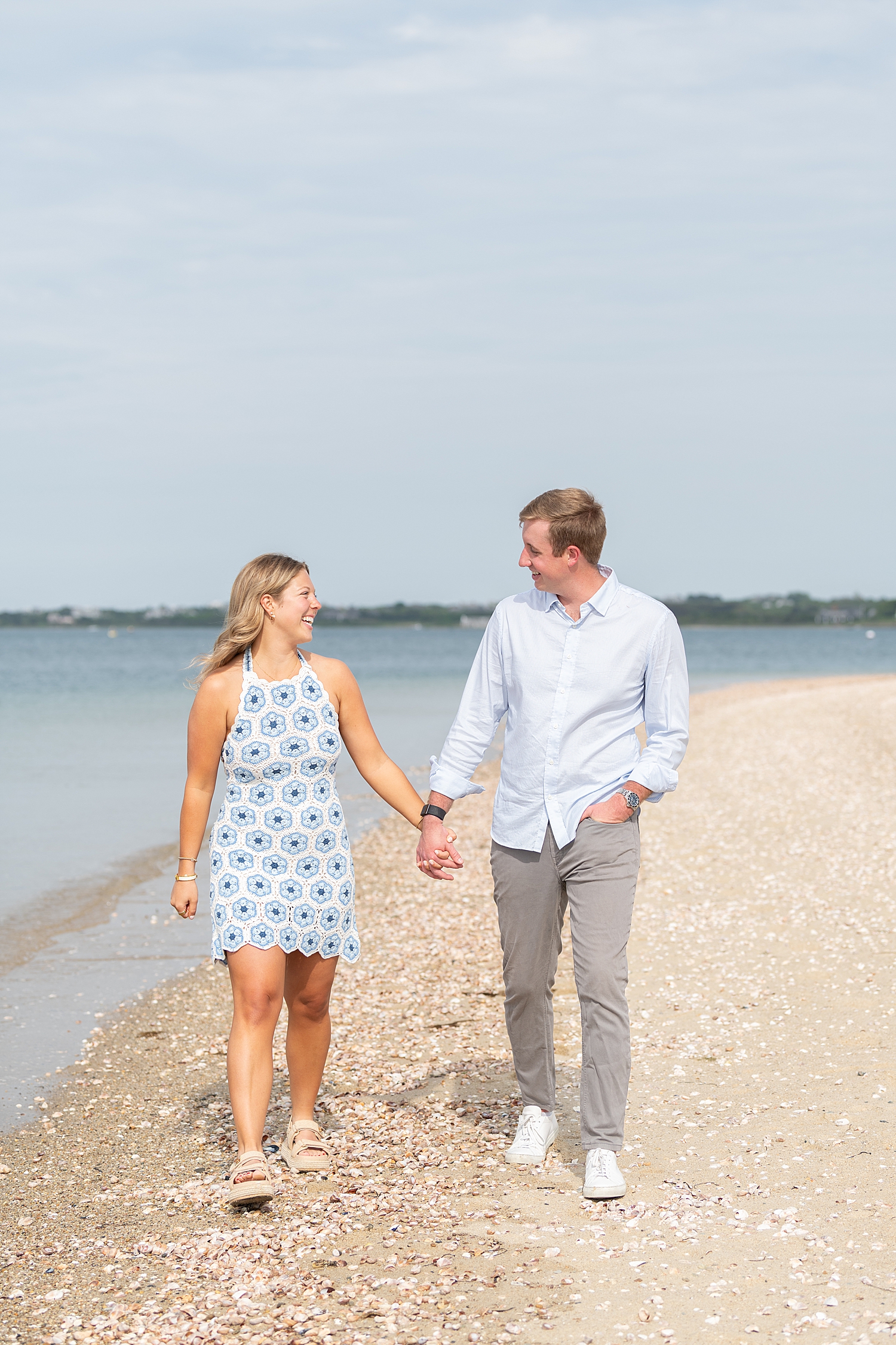 couple walk hand in hand down the beach after proposal at Brant Point Lighthouse