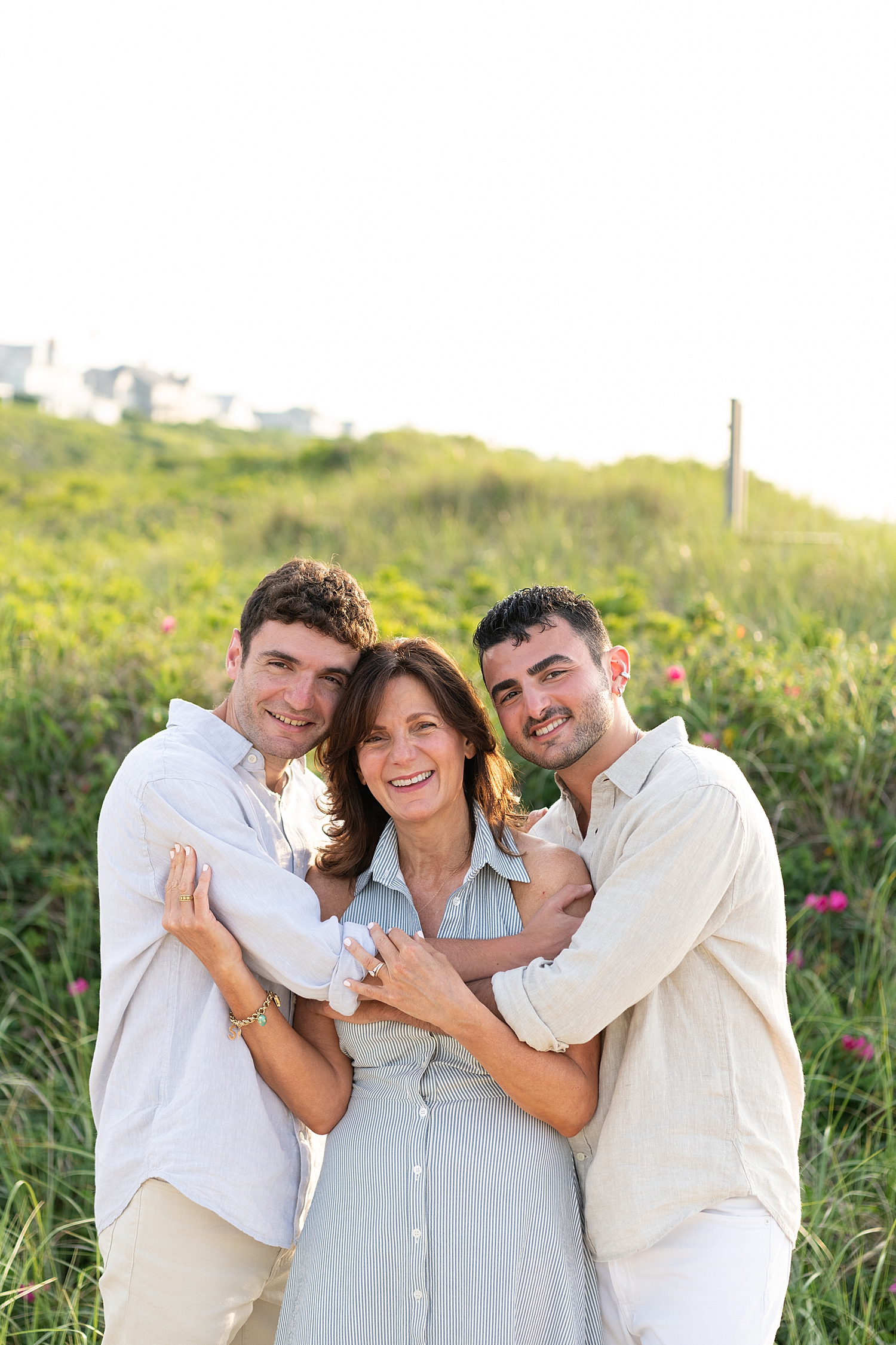mother is embraced on each side by grown sons for extended family session