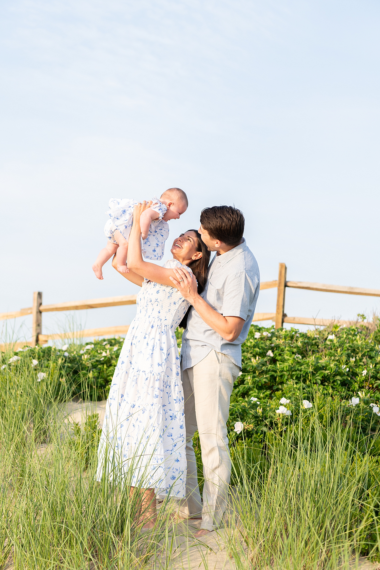 parents lift up their baby while standing in the sea grass by Rachel Elizabeth Co