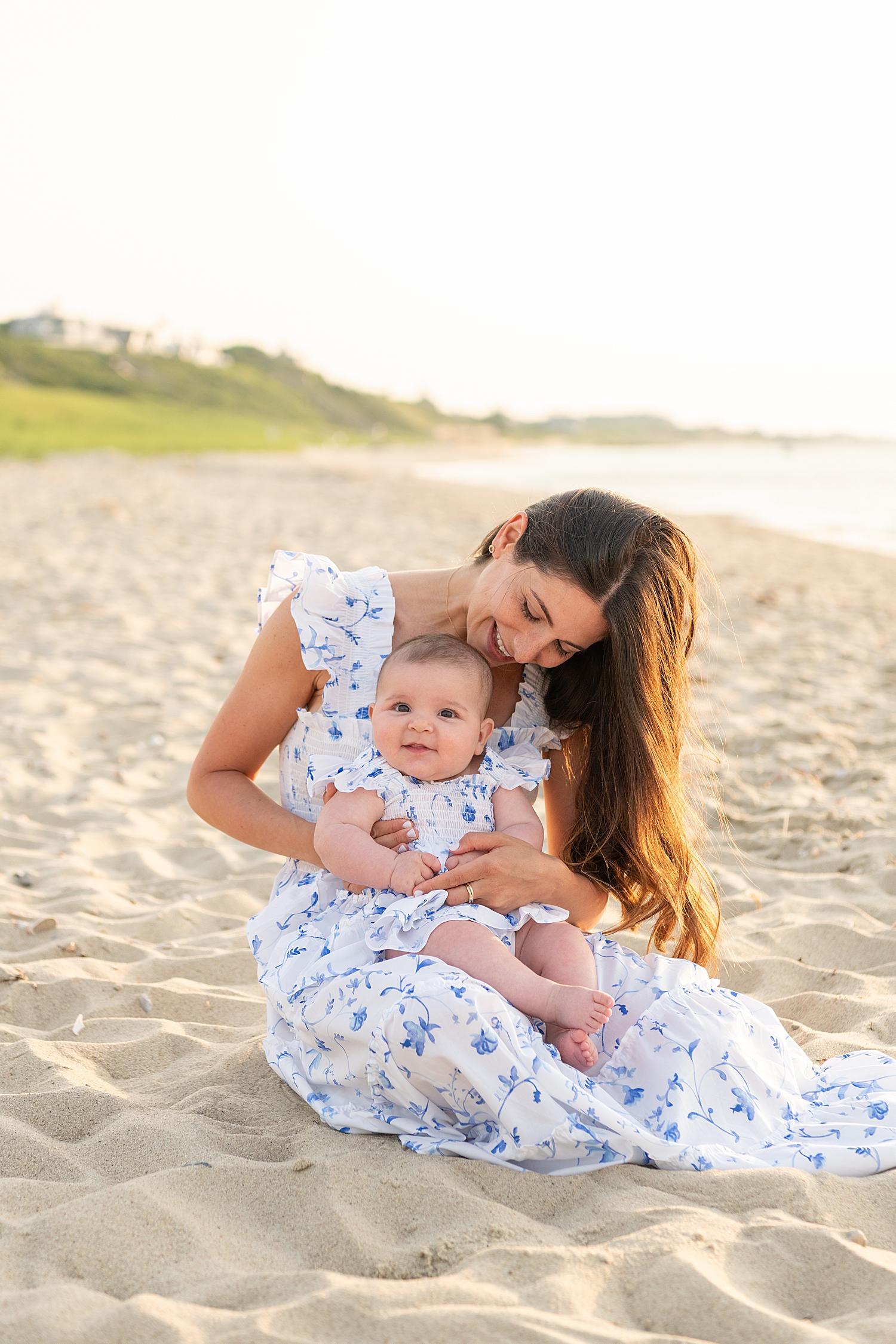 mother plays on the beach with her baby for extended family session
