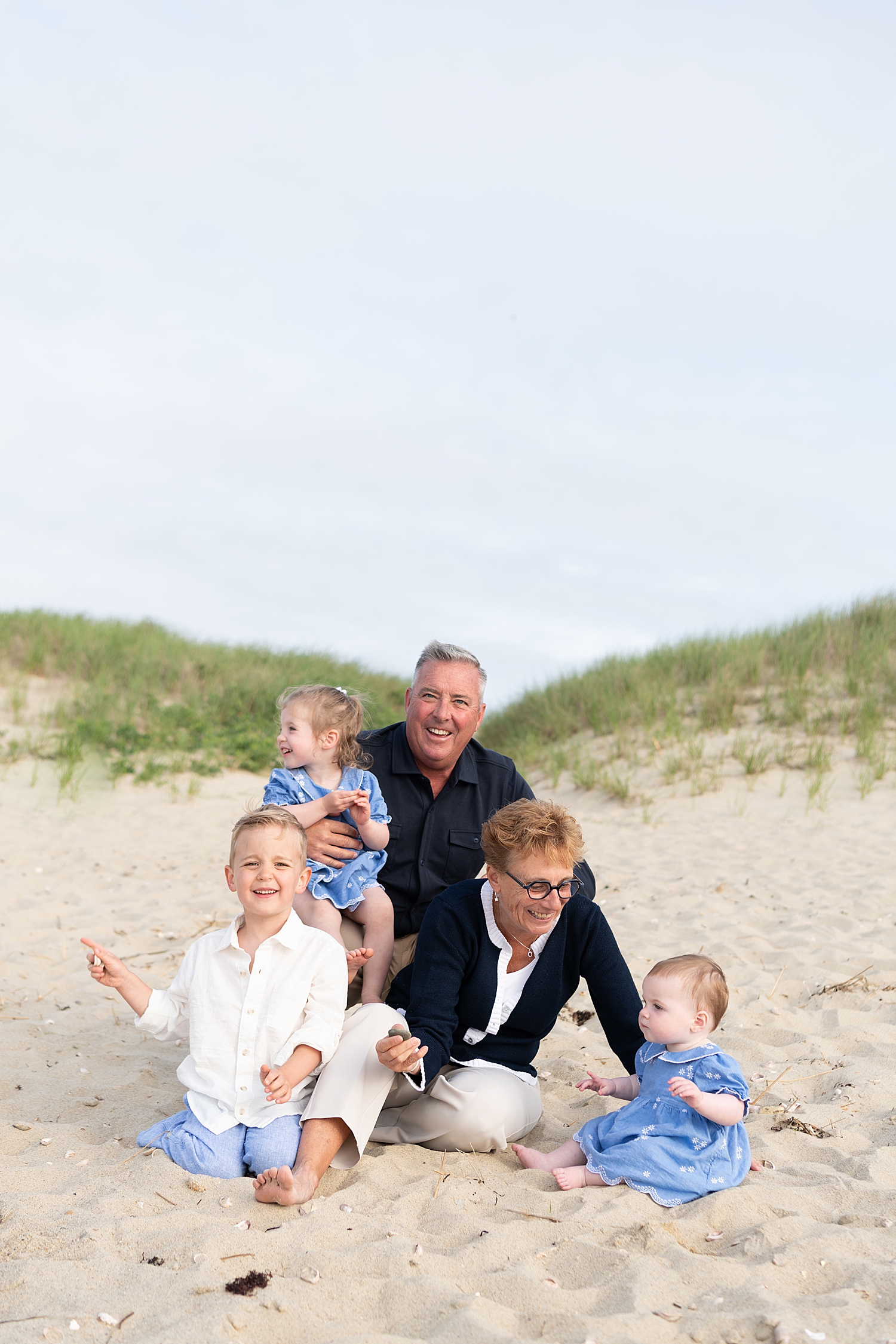 grandparents sit in the sand with their grandbabies by Rachel Elizabeth Photography