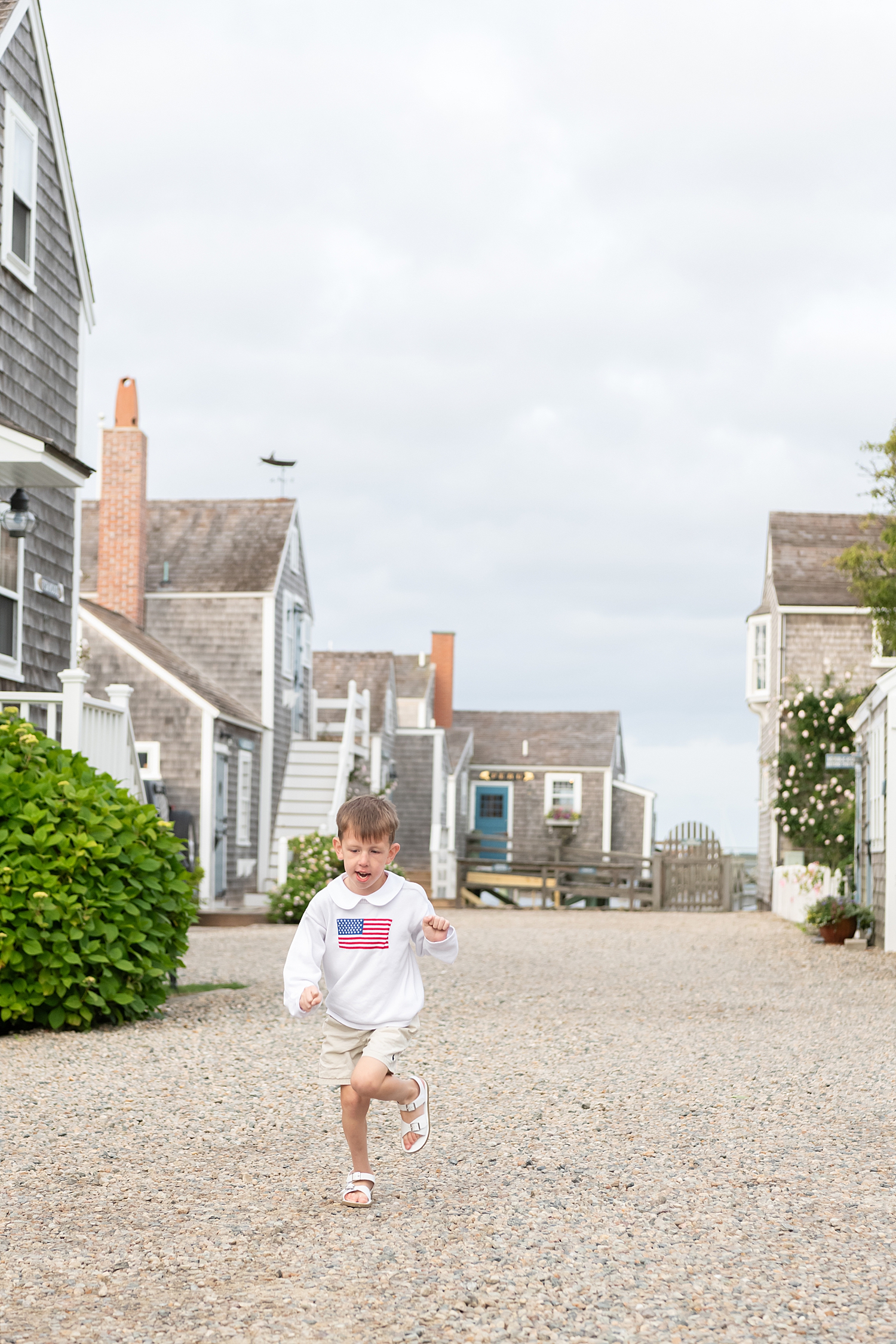 little boy runs down old street by Nantucket Family Photographer