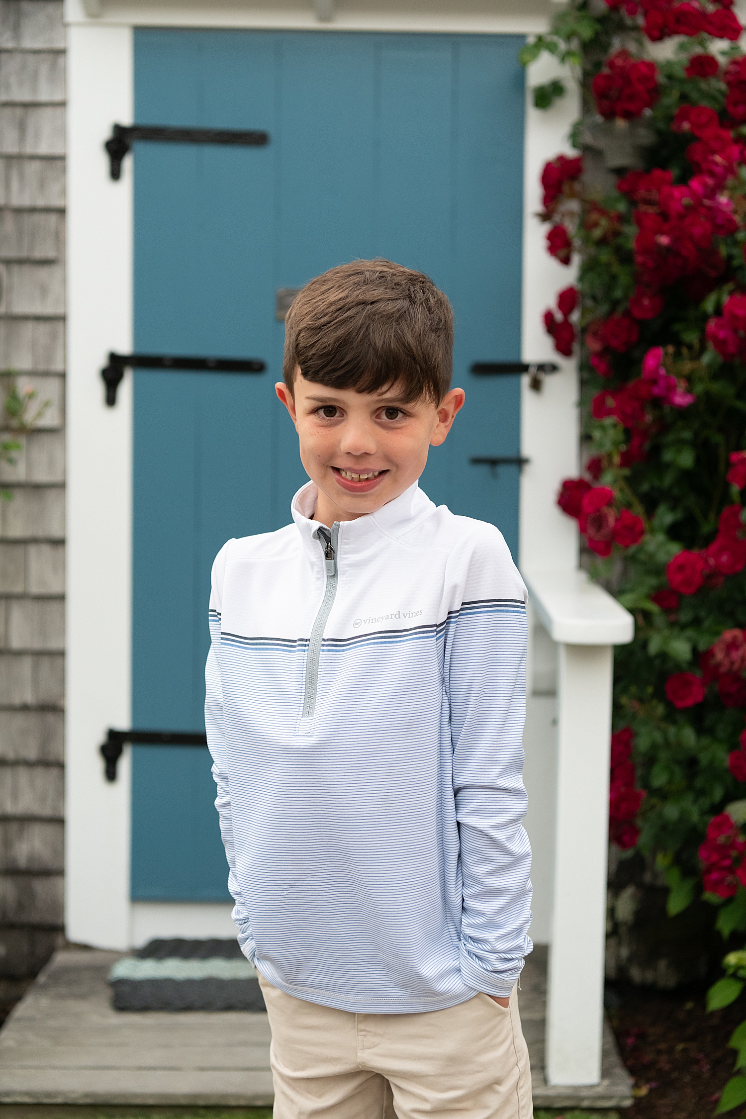 small boy in blue shirt in front of blue door at Old North Wharf