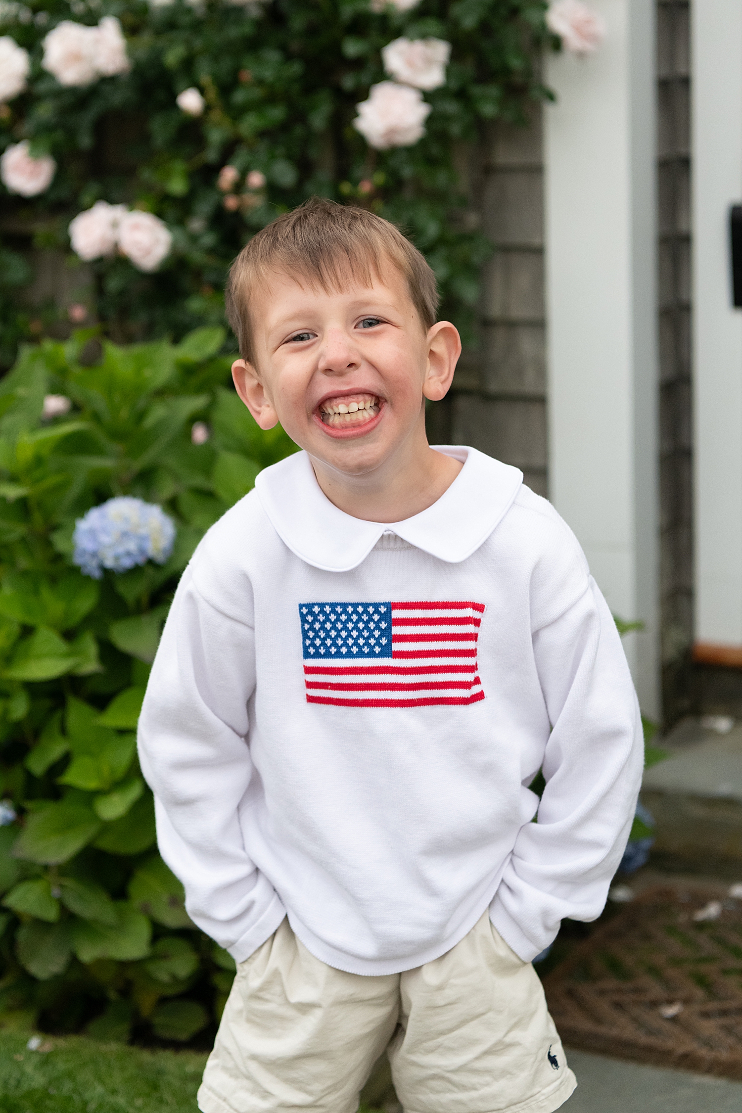 little boy with American flag sweatshirt in front of flowers by Nantucket Family Photographer