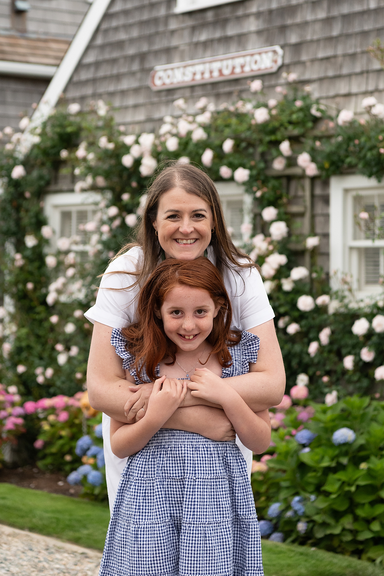 mother leans over daughter and wraps her in hug by Rachel Elizabeth Photography