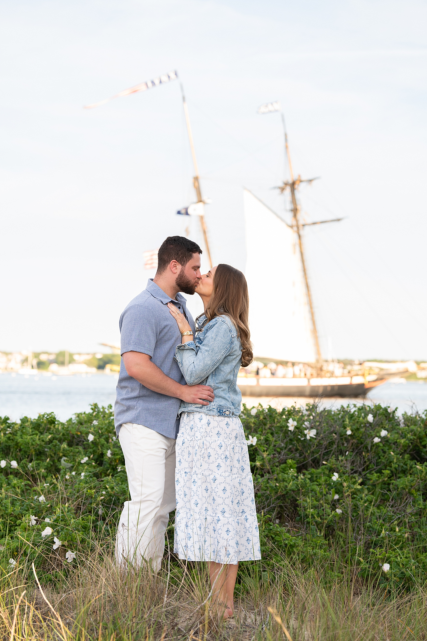 couple share a kiss in front of boat after getting engaged by Nantucket family photographer