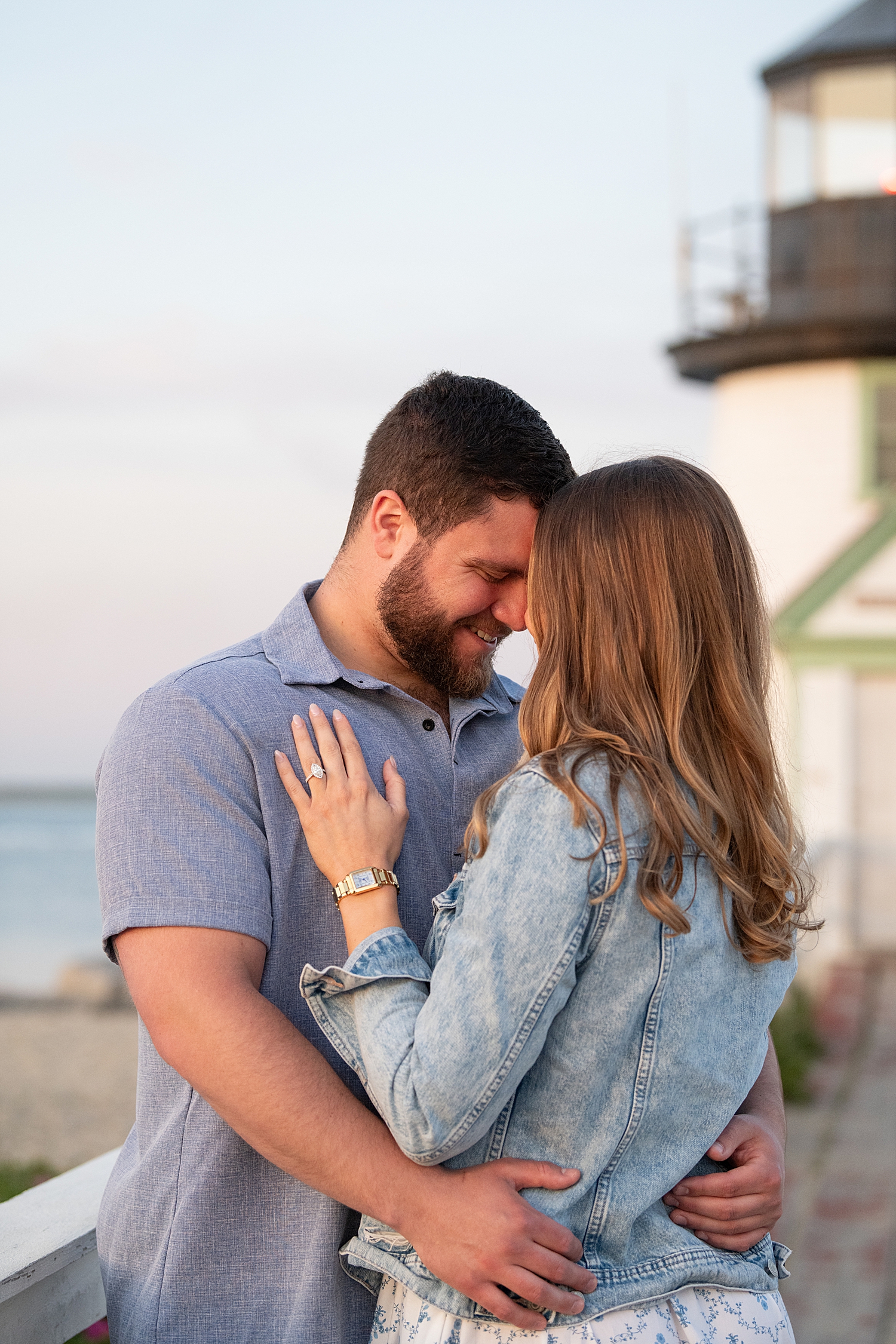 couple embraces closely in setting sunlight for Sunset Proposal at Brant Point Lighthouse
