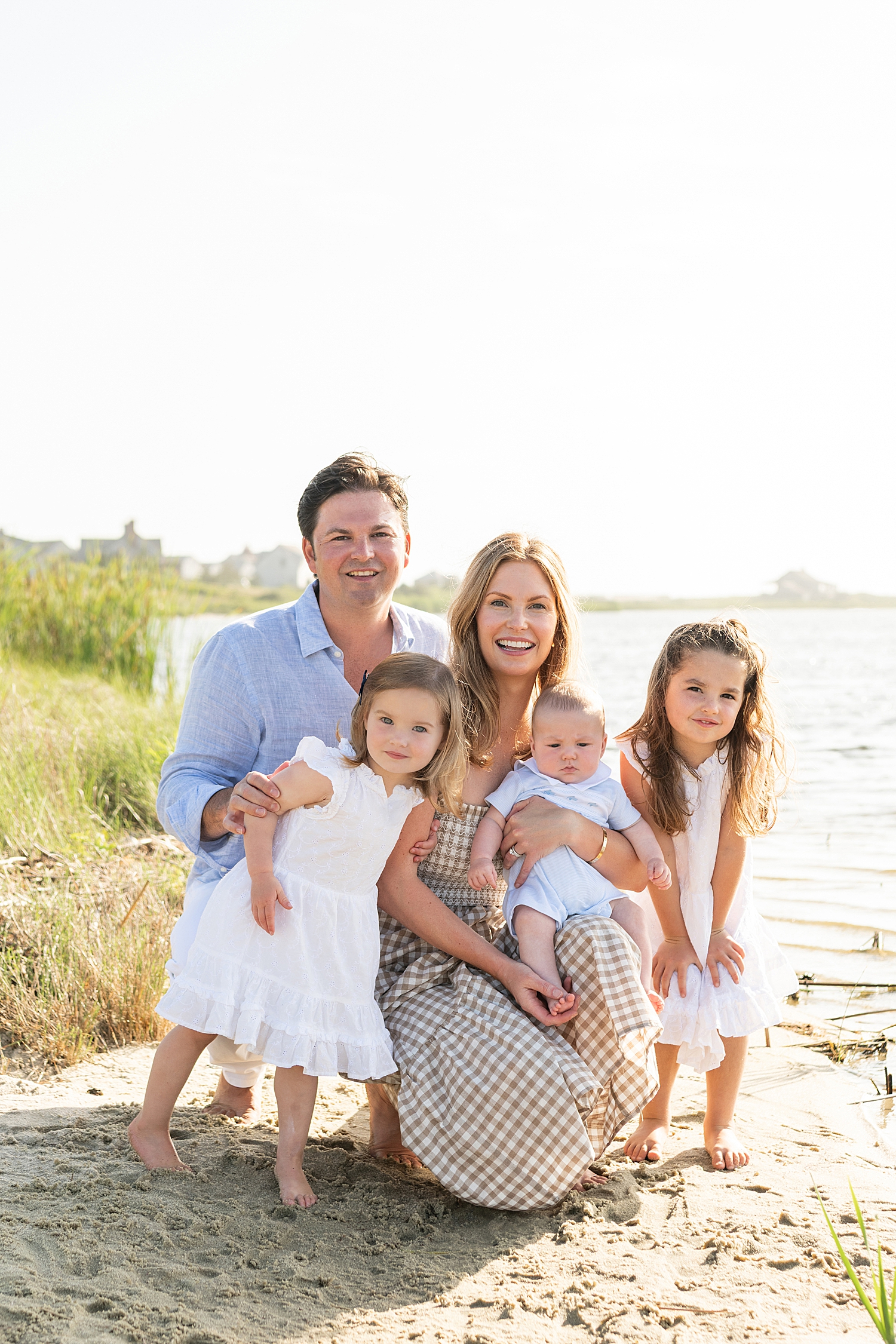 family of five kneels on beach after learning what to wear