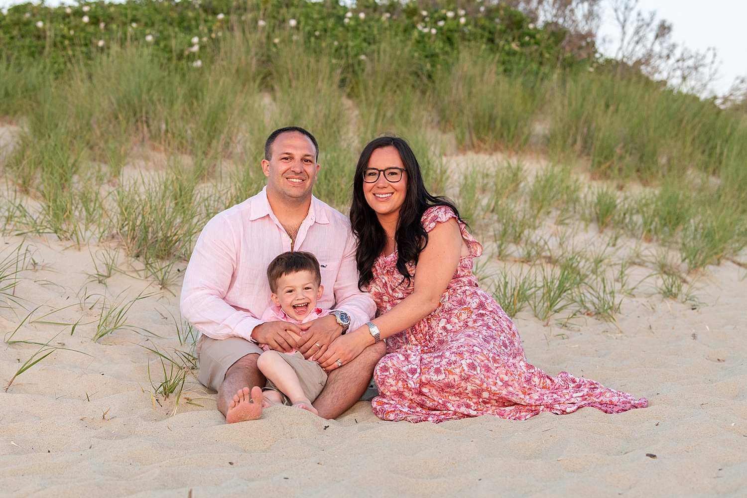 father and mother sit with their baby in the sand by Rachel Elizabeth Photography