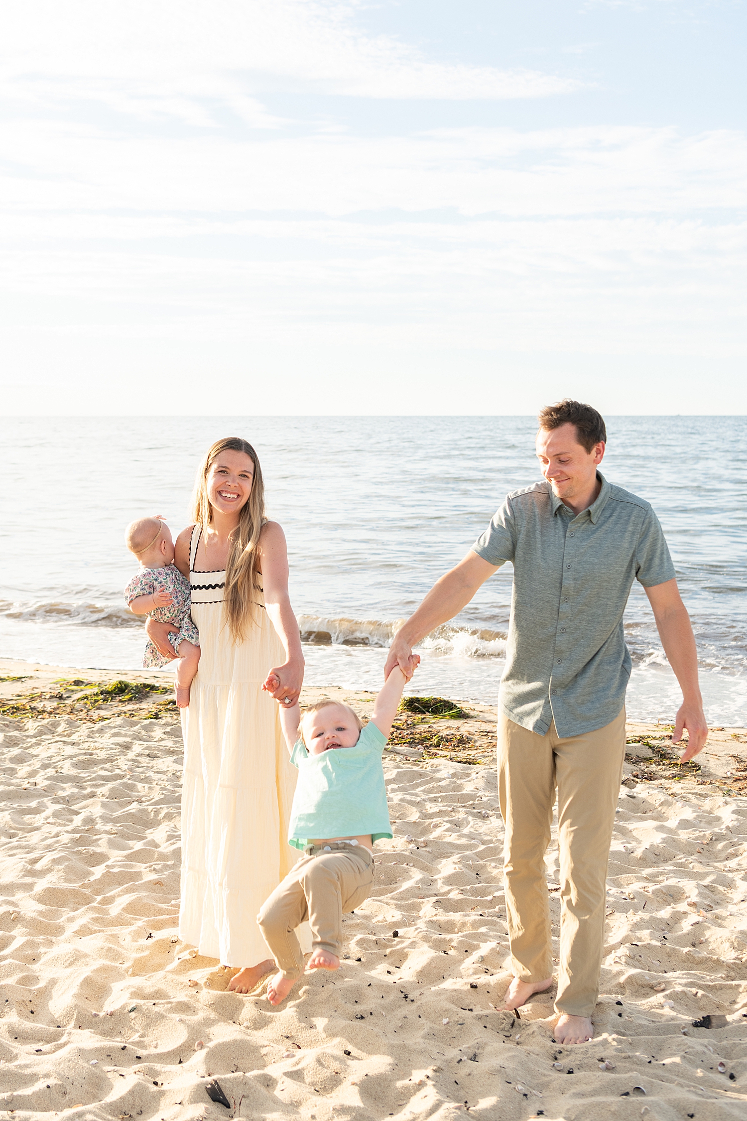 mom and dad swing toddler in arms on beach by Nantucket family photographer