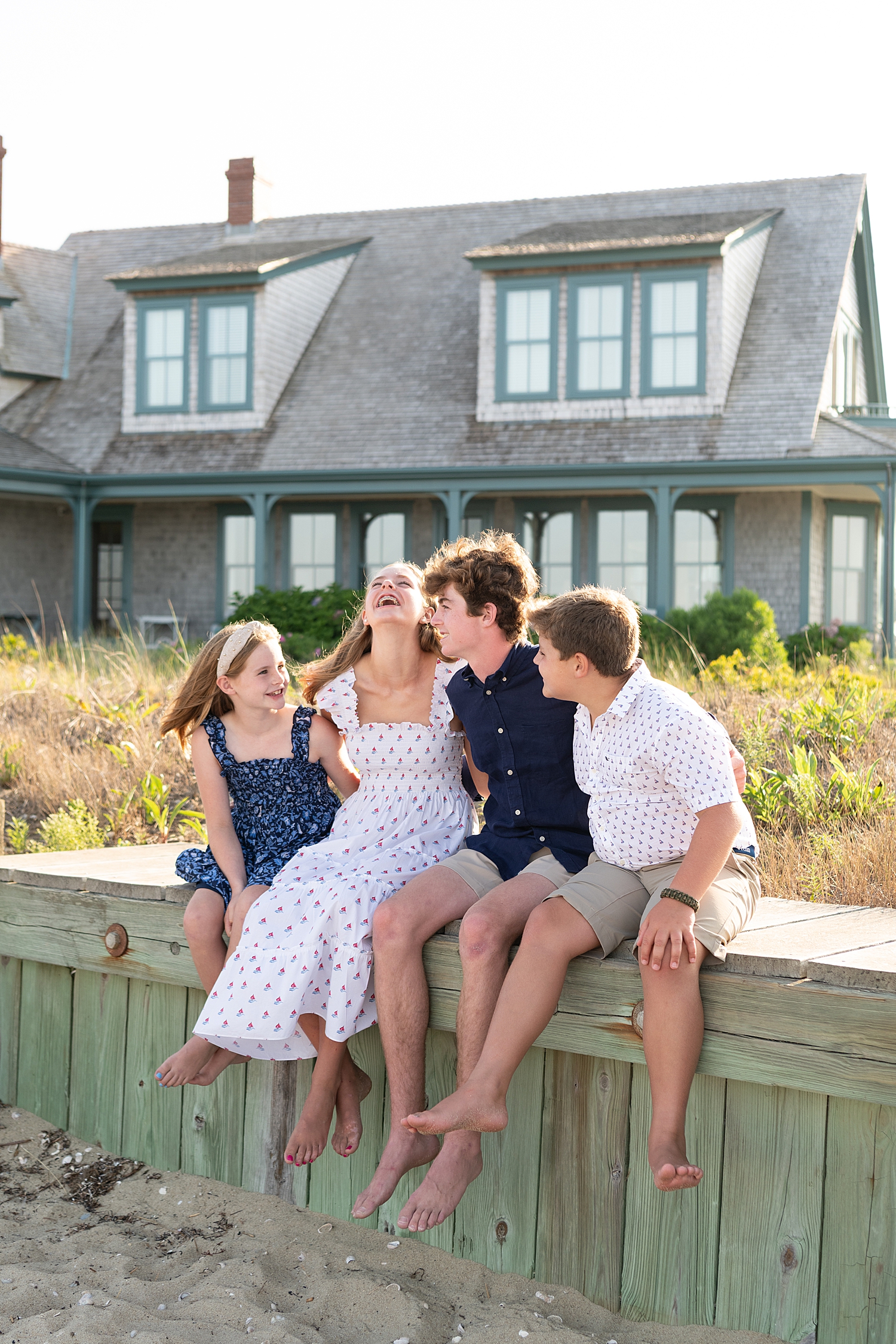 four children sit on ledge in front of beach house laughing showing how to personalize your session