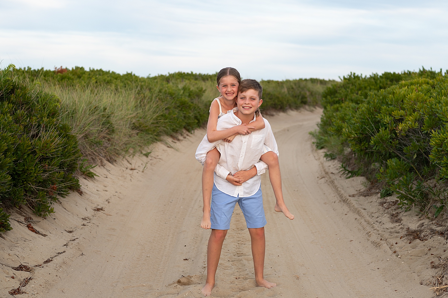 siblings do piggy back rides by the beach by Rachel Elizabeth Photography