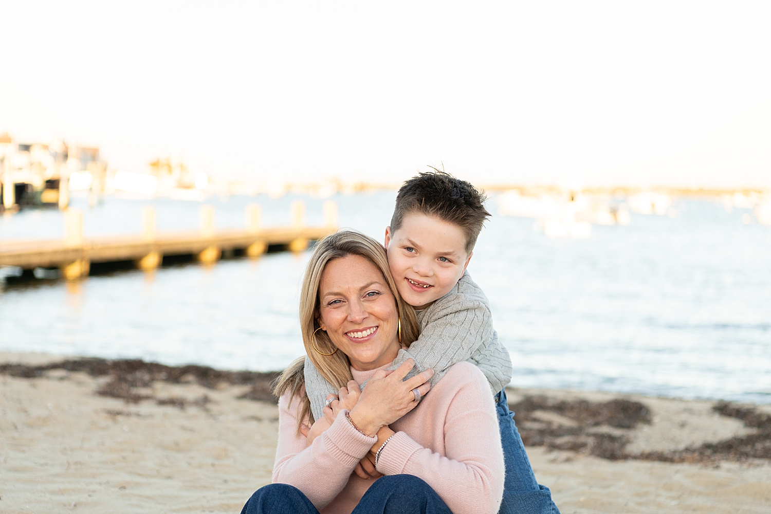 young son hugs mother in front of beach by Nantucket portrait photographer