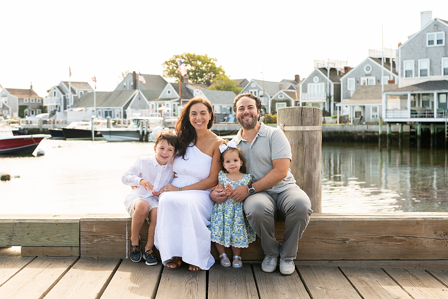 parents sit with their young children on dock over water by Rachel Elizabeth Photography