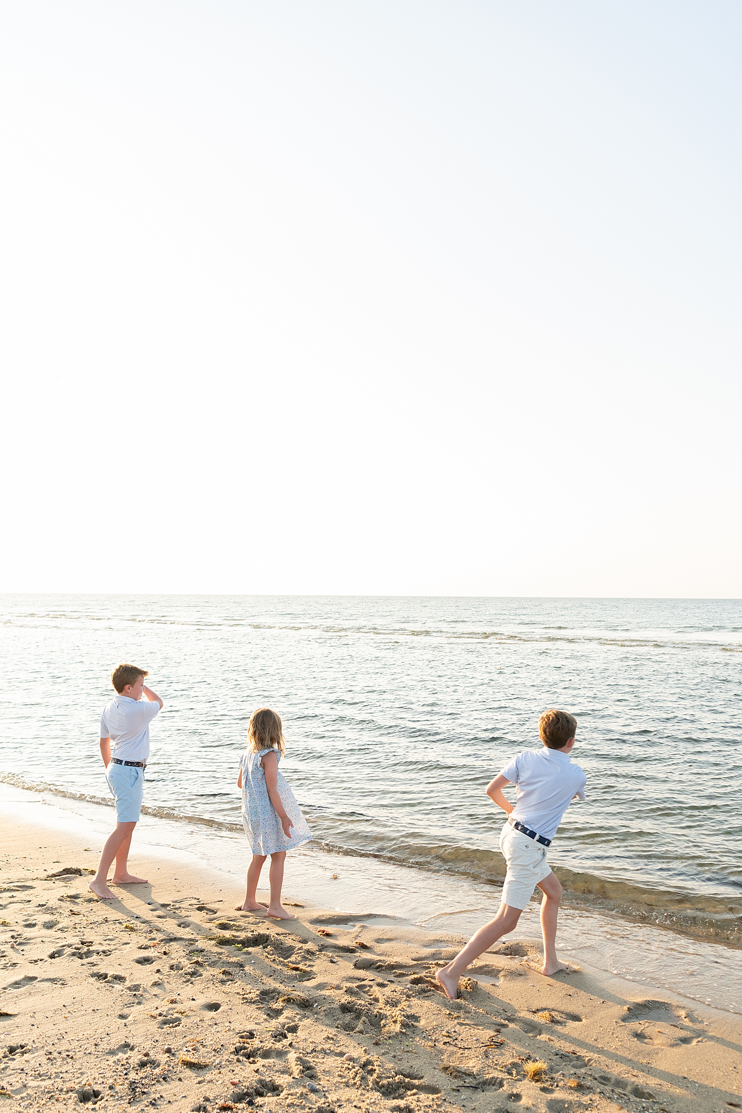 three kids throw rocks into the sea by Rachel Elizabeth Photography