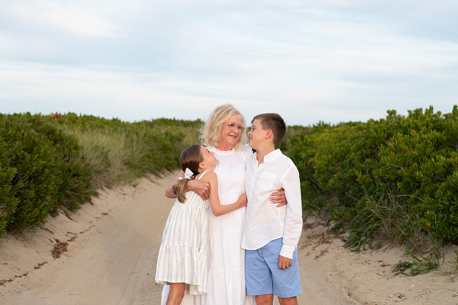 grandmother looks at two grandkids on sand by Nantucket portrait photographer