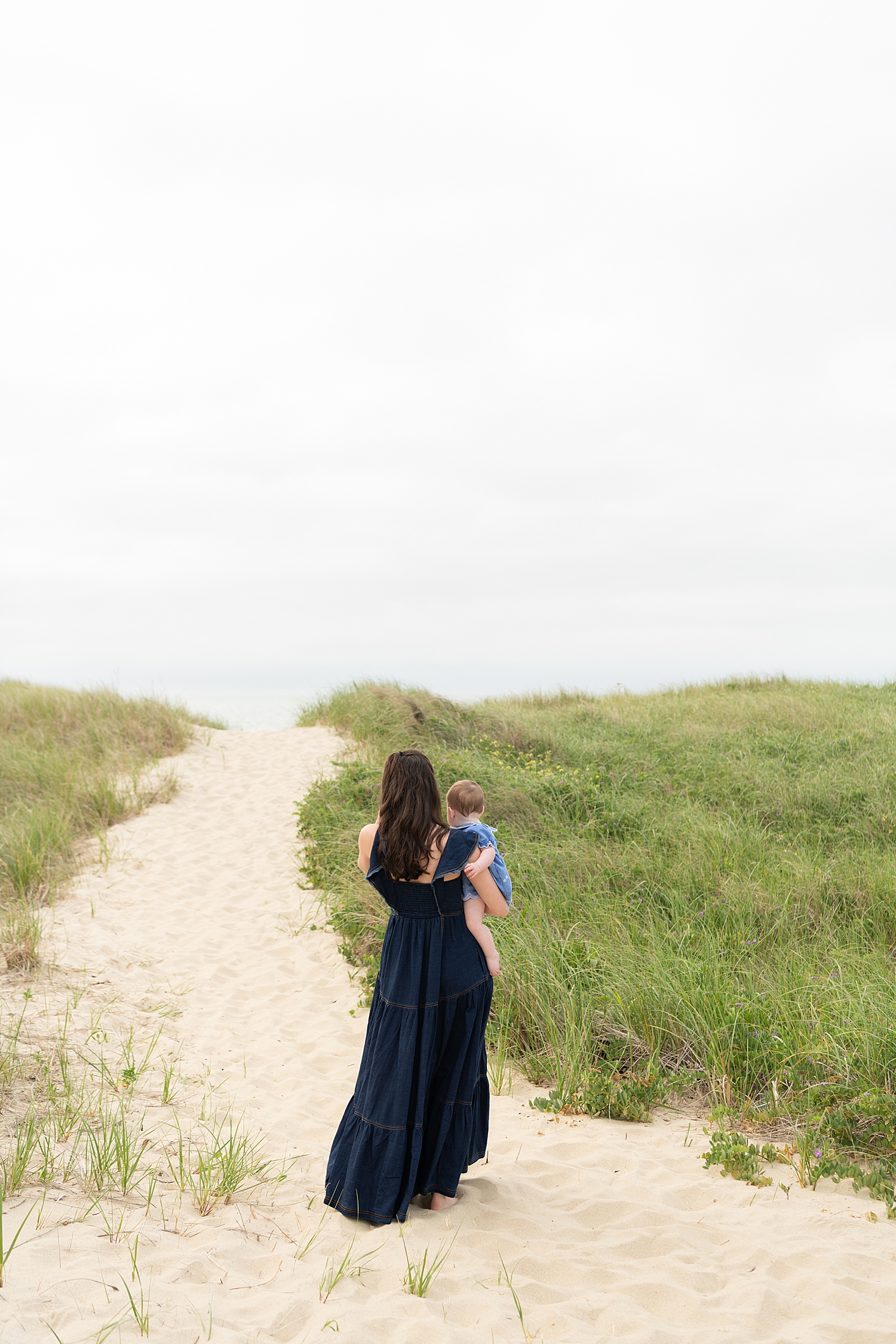 mother carries baby up sand for Summer session at Washing Pond Beach