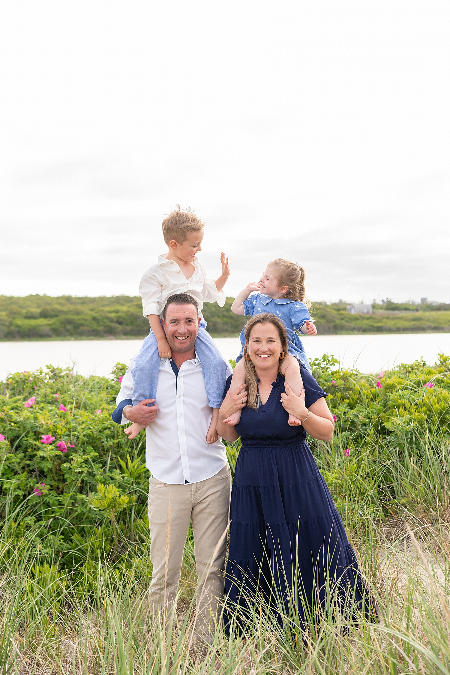 mom and dad hold toddlers on their shoulders for Summer session at Washing Pond Beach