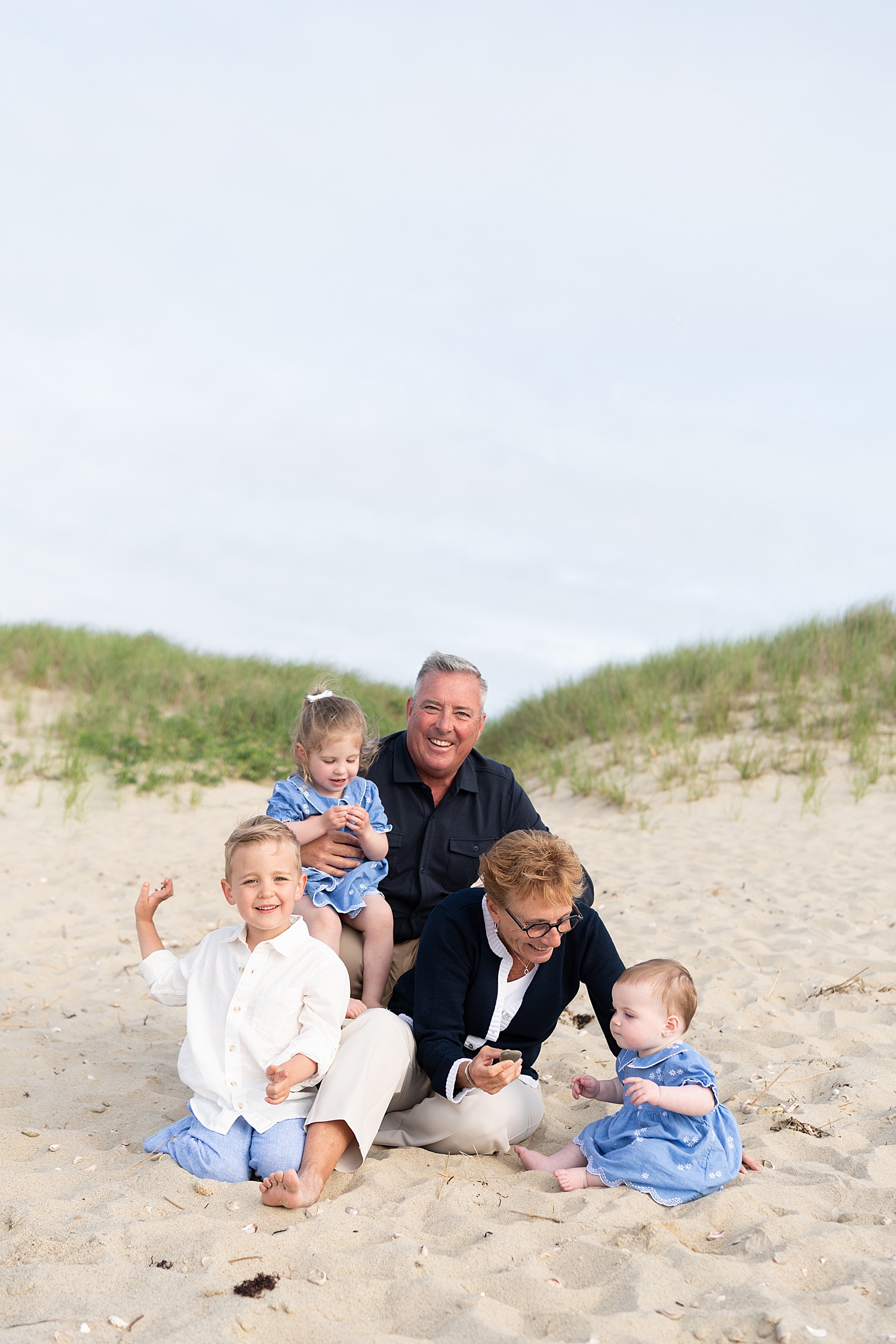 grandparents play with children next to the ocean by Nantucket Family Photographer