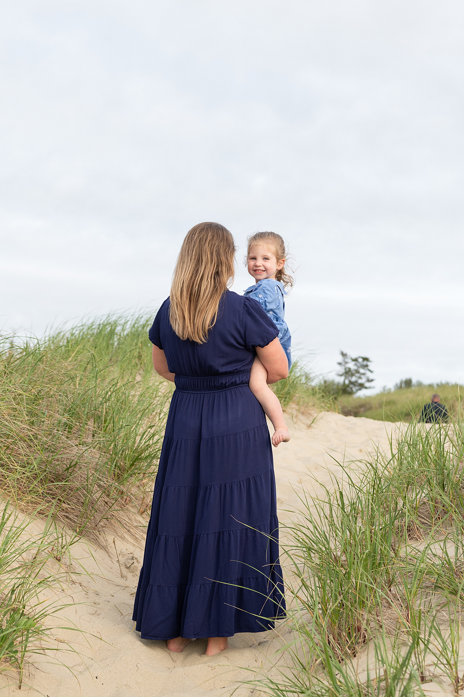 mother carries her toddler up sand by Nantucket Family Photographer