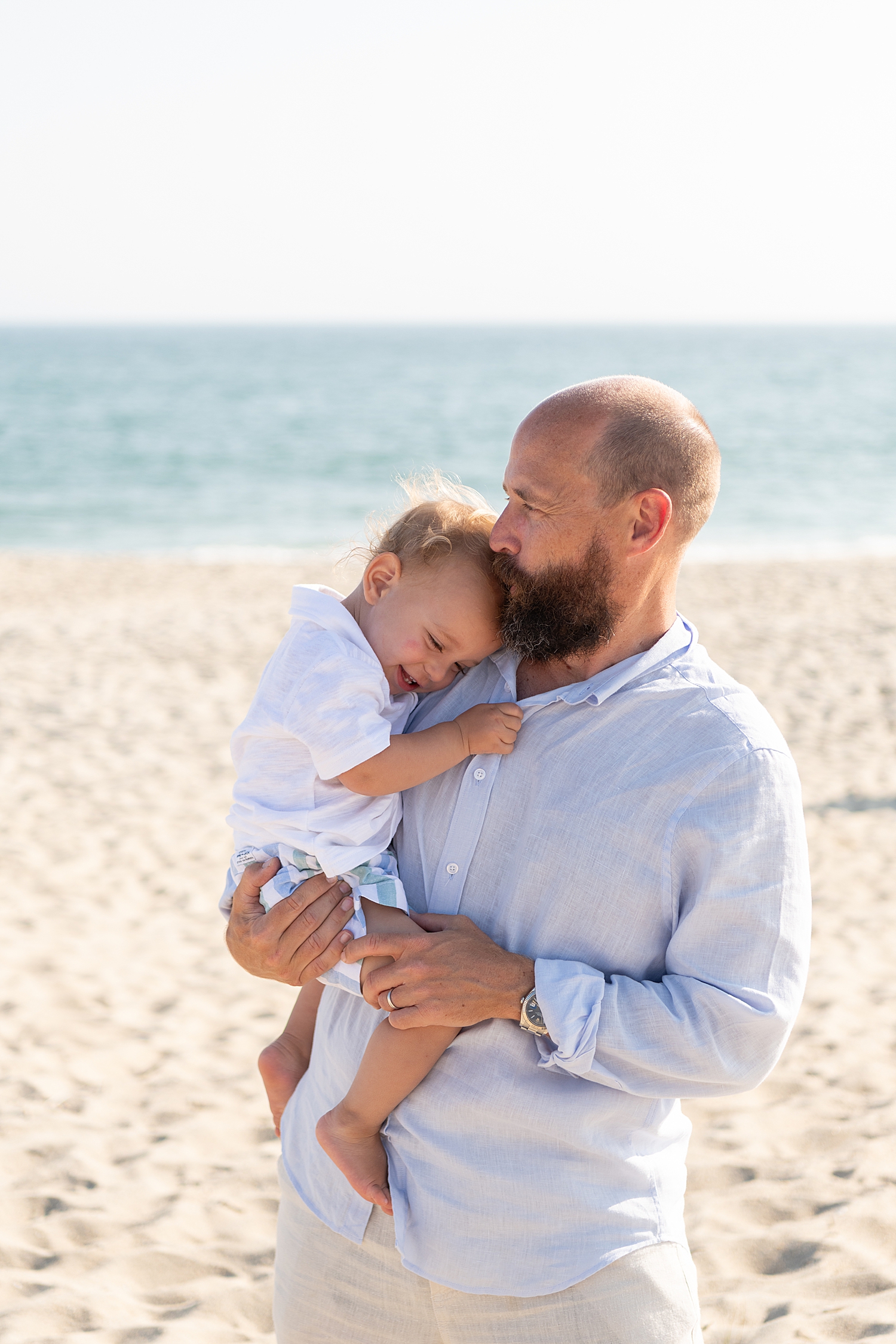 father holds his one year old son who snuggles his shoulder by Rachel Elizabeth Photography