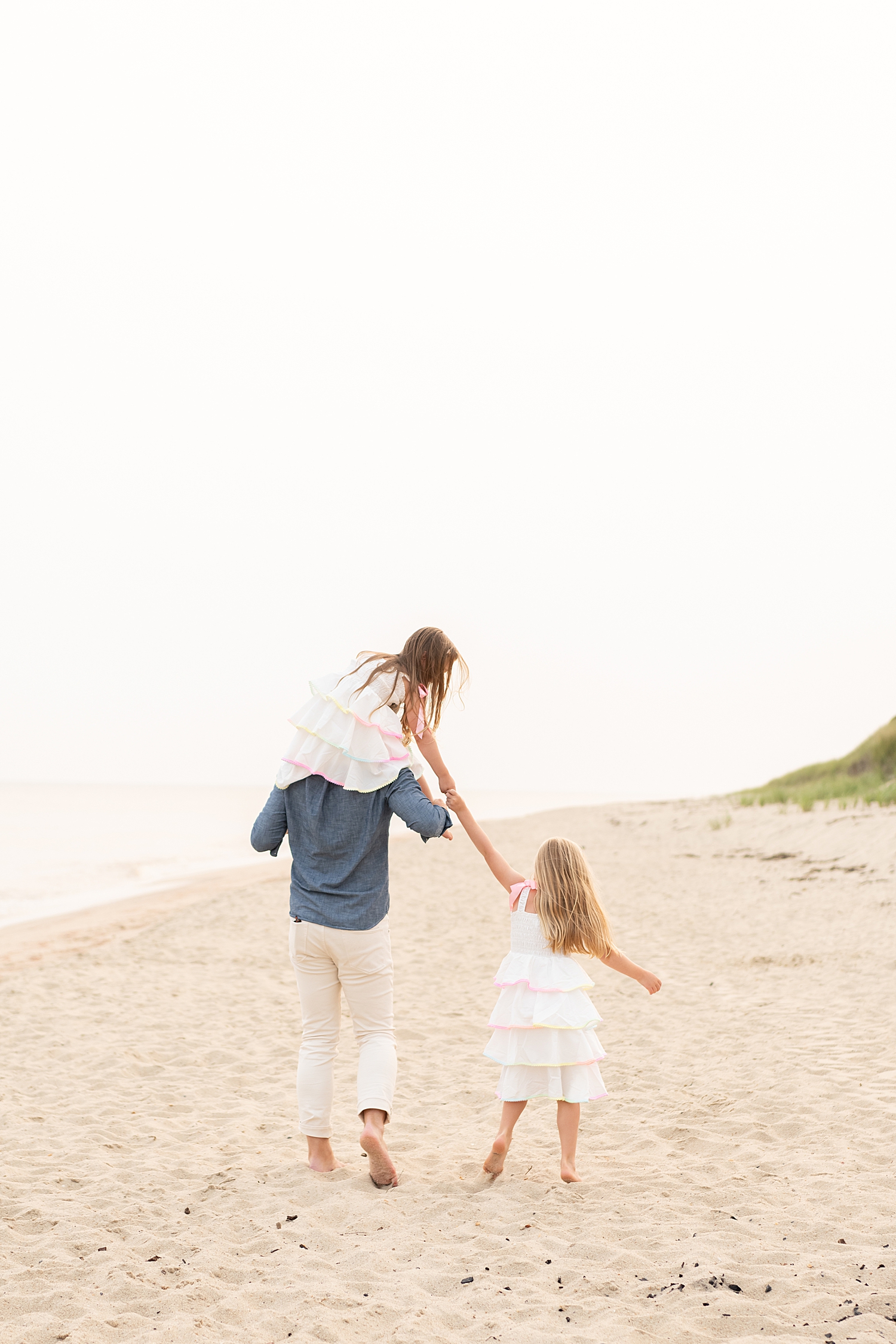 dad runs down the sand with two daughters at Tom Nevers Beach