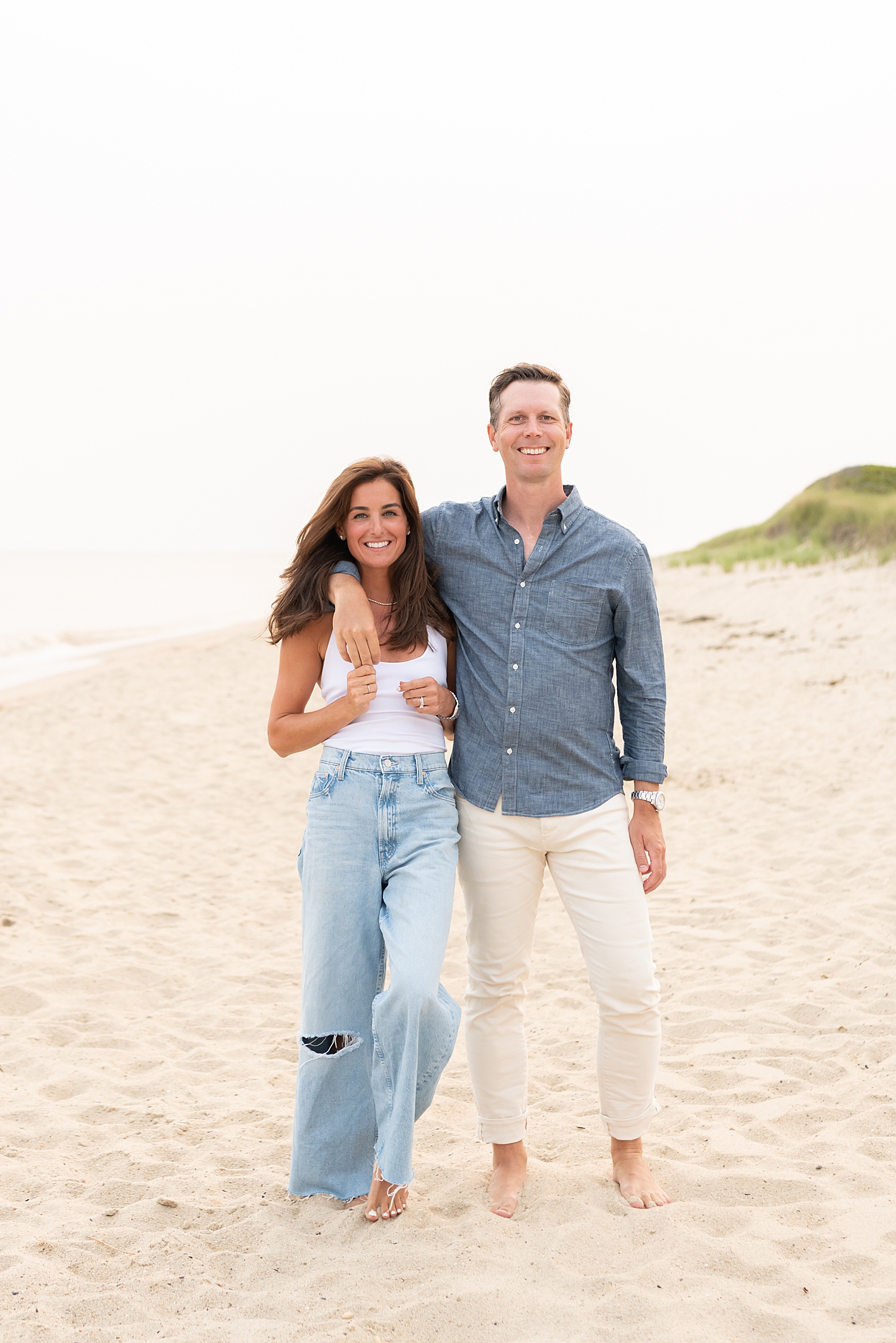 mom and dad stand together on the sand by Rachel Elizabeth Photography