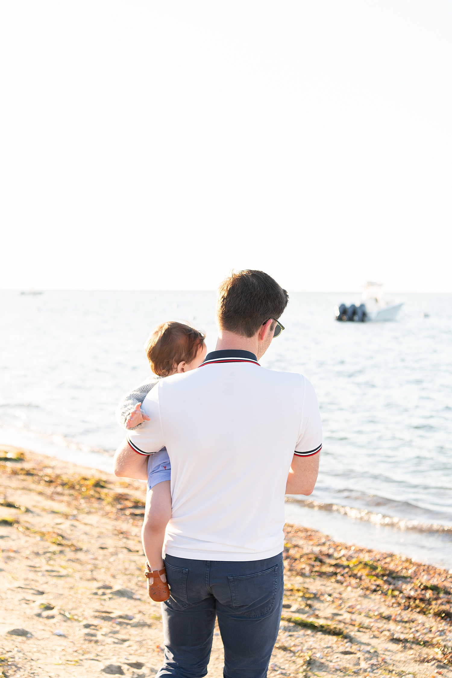 dad walks next to the water holding his baby by Nantucket family photographer