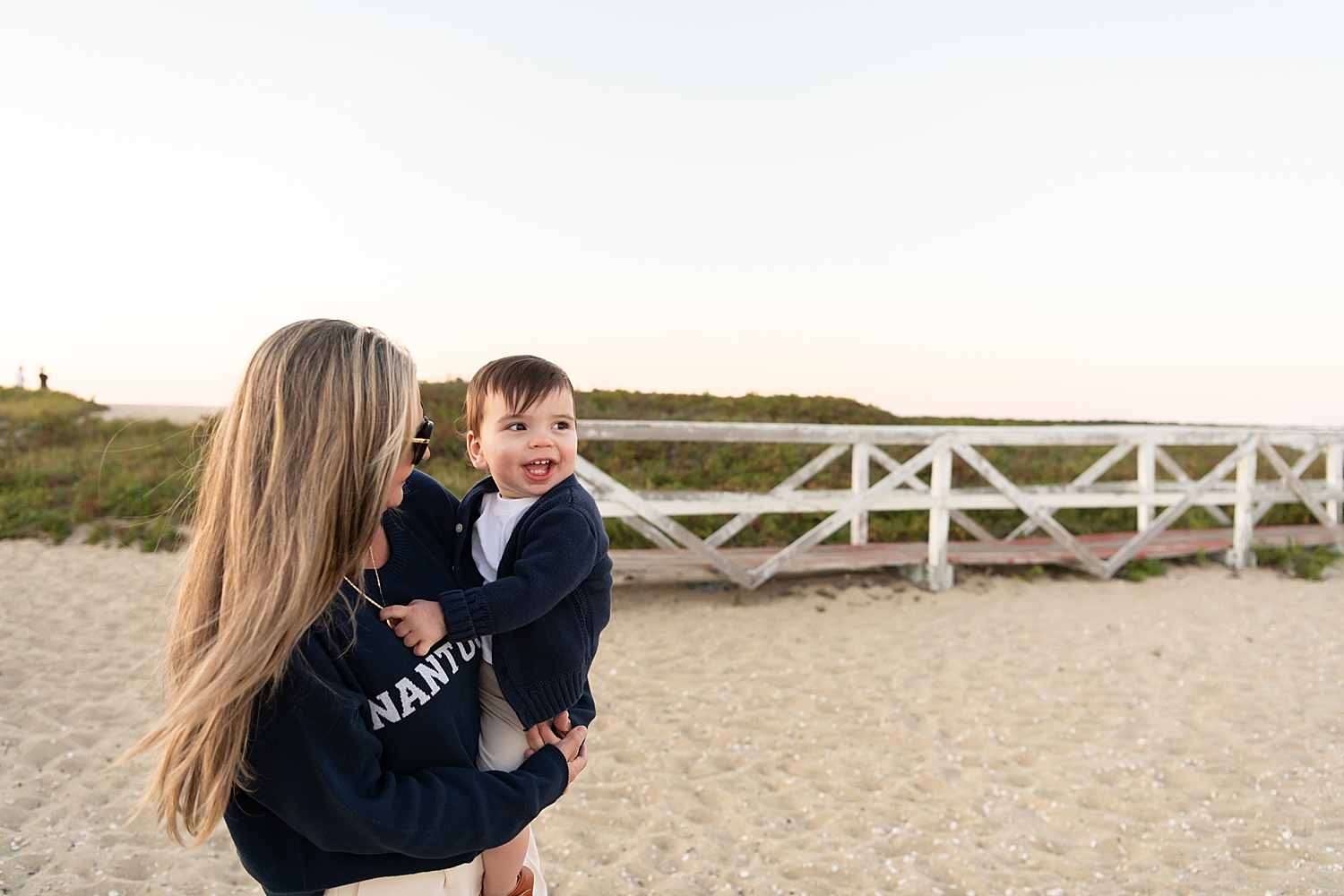 little one in cardigan held by grandma in sweatshirt on the sand by Rachel Elizabeth Photography