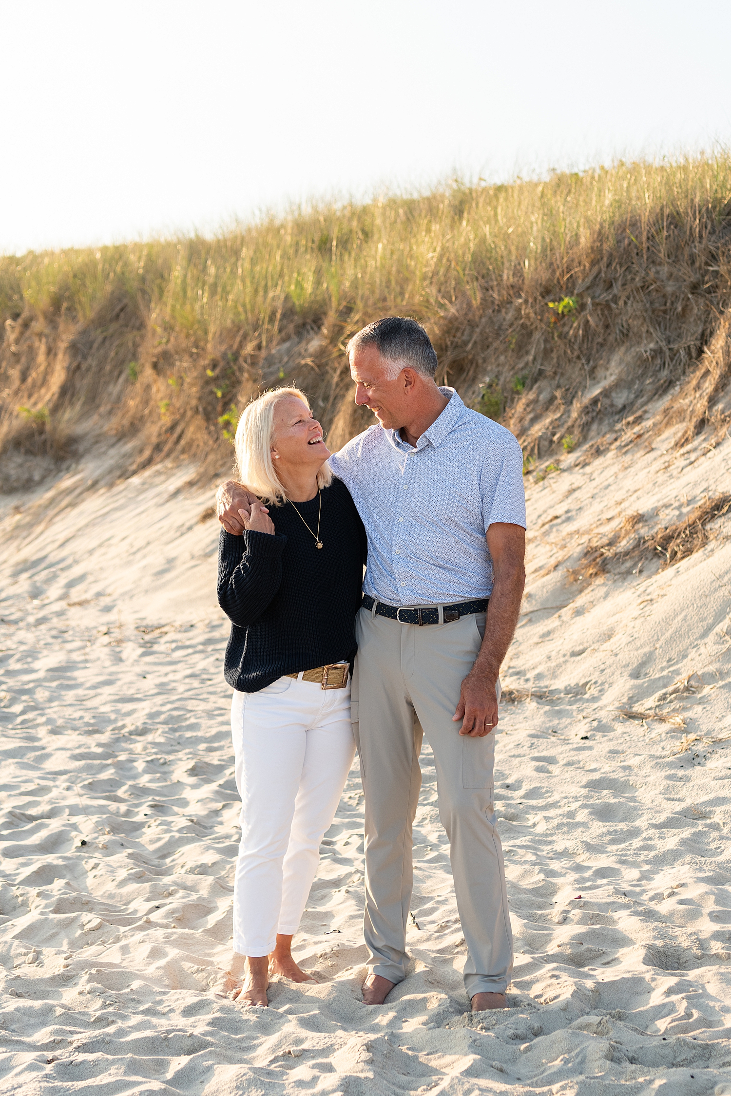 older couple embrace next to sand bank by Nantucket family photographer