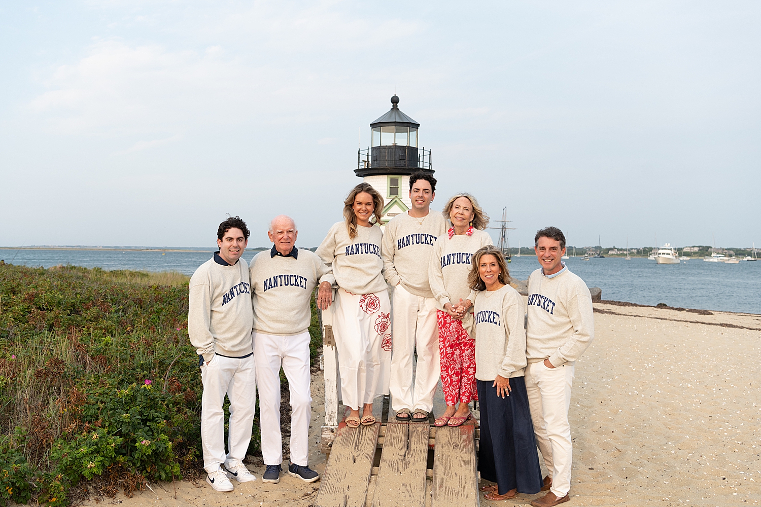 group of people in matching sweatshirts in front of lighthouse by Nantucket family photographer