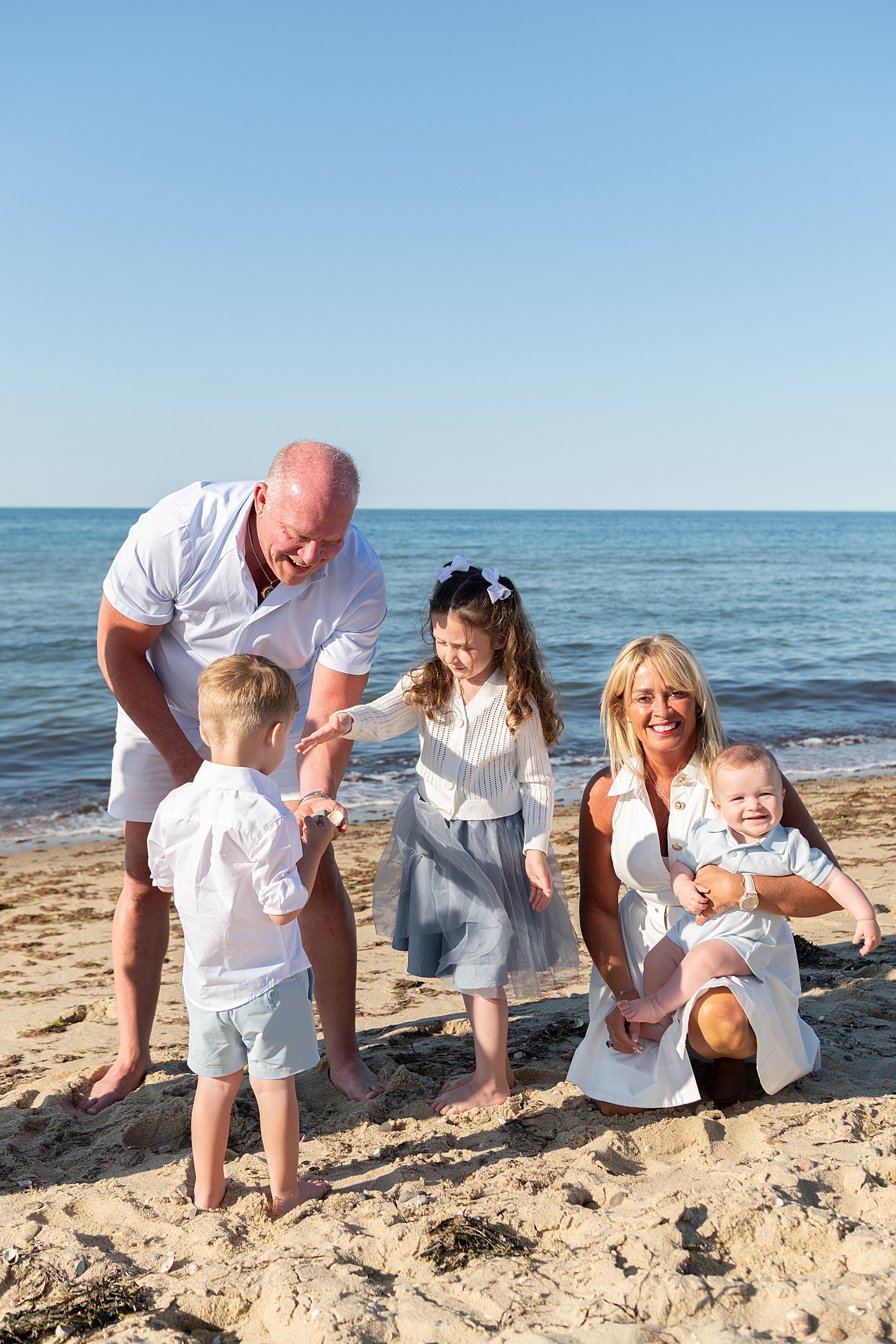 grandma and grandpa play with kids on beach by Nantucket family photographer